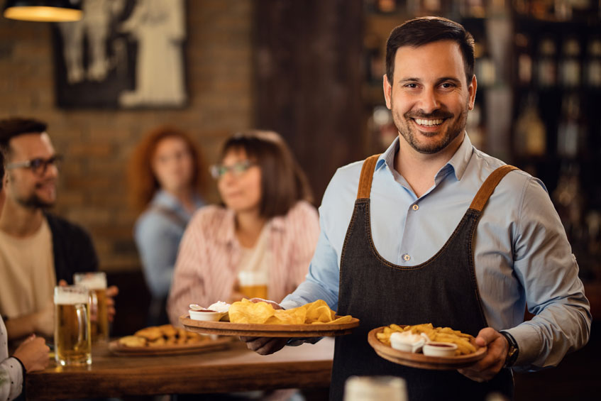 Laughing waiter with plates in both hands